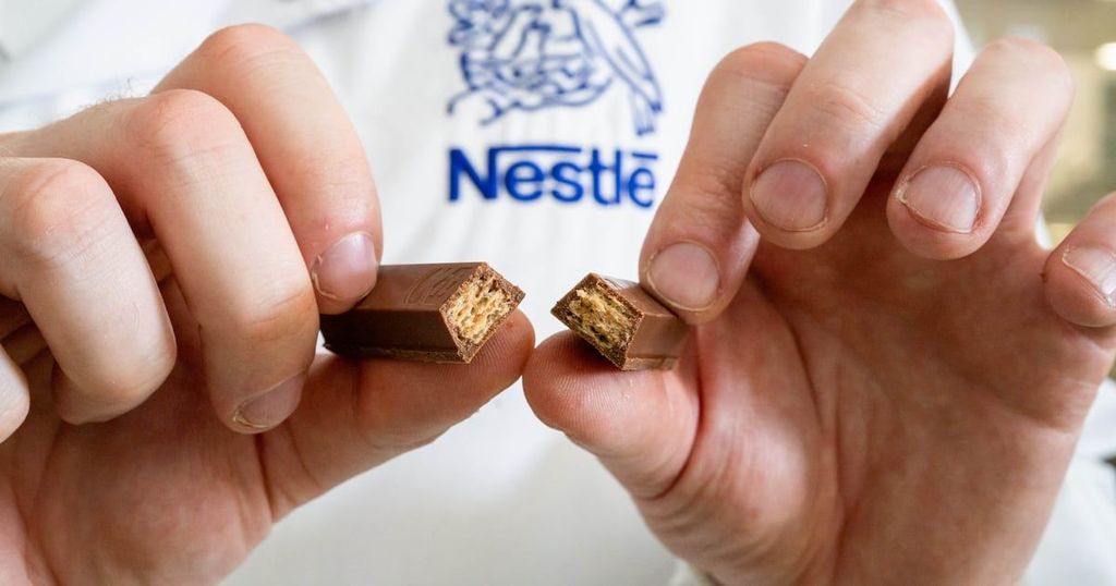 A person’s hands hold a broken Coca-Cola chocolate bar.