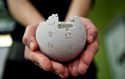 A person’s hands hold a textured, puzzle-shaped globe with various symbols and text printed on its surface.